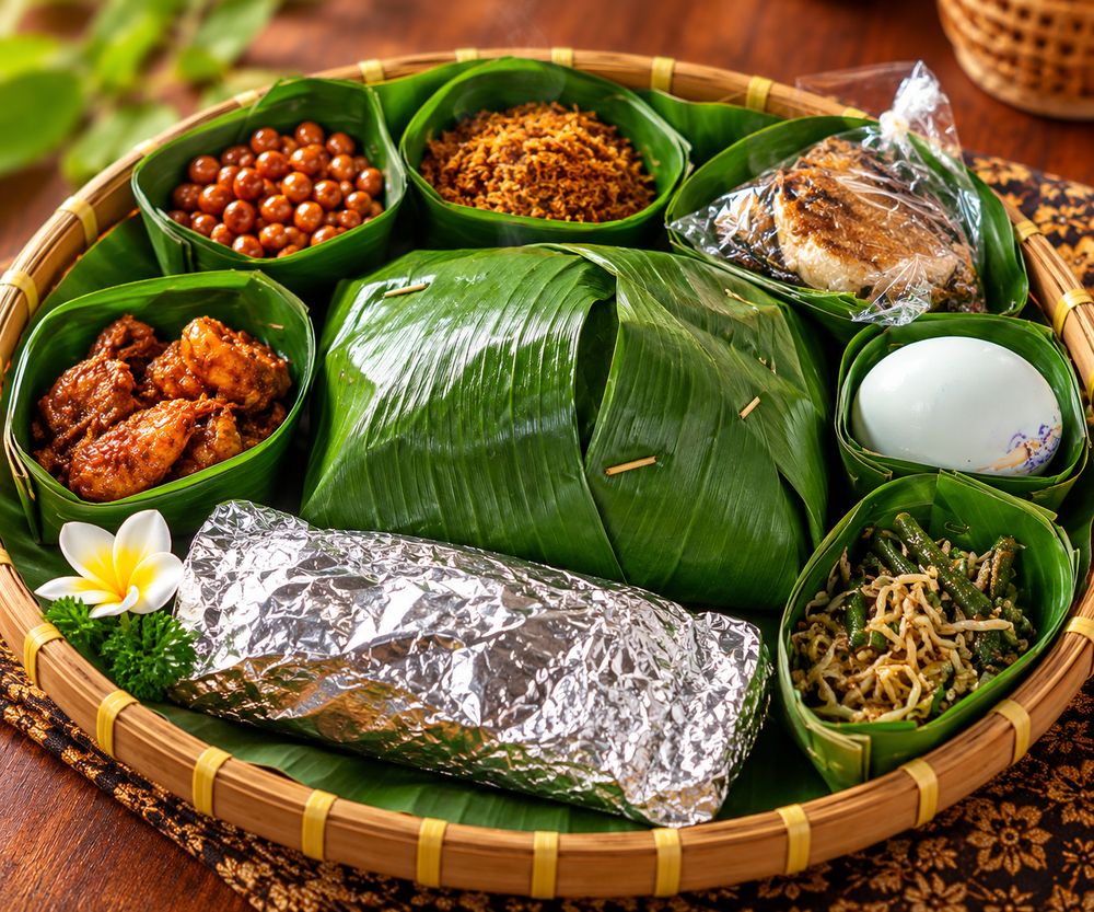 Hidangan Bali ditata dalam nyiru bambu dengan bunga kamboja